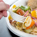 A hand holding a 7 1/8" Heavy Weight cornstarch fork over a pasta salad.