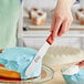 A person using a Choice baking spatula to cut a cake.