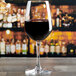 An Anchor Hocking Florentine II wine glass filled with red wine on a table in a bar.