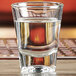 An Anchor Hocking double shot glass filled with water on a table.