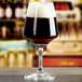 An Anchor Hocking stemmed beer glass filled with beer on a table in a bar.