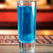 A close up of an Anchor Hocking shooter glass filled with blue liquid.