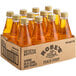 A box of Rose's Peach Syrup glass bottles on a table in a grocery store aisle.