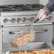 A person using a Backyard Pro twin fryer basket to cook fries.