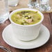 An Ivory bouillon cup filled with soup on a white plate.