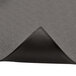 A black anti-fatigue mat with a pebble texture and a black leather corner on a grey surface.