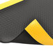 A black rubber anti-fatigue mat with yellow edges and a yellow diamond pattern.