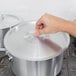 A hand holding a Vollrath metal lid on a silver pot.