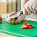 A person using a Choice Classic paring knife to cut strawberries on a cutting board.