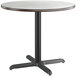 A Lancaster Table & Seating round table with a white surface and black base.