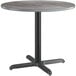 A Lancaster Table & Seating round table with a black base and slate grey top.