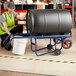 A man using a Lavex steel drum hand truck to move a barrel.