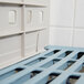 A Metro white and blue plastic shelf divider with a blue handle on a wire shelf.