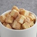 A bowl of brown and white cubes of baked cheesecake.