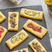 A rectangular food item with Geefree Puff Pastry Dough with different toppings on a black surface.