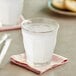 A glass of Old Orchard limeade concentrate in water with ice on a napkin.