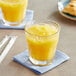 A close-up of a glass of Old Orchard Orange Juice concentrate with a straw.