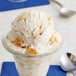 A glass cup with a scoop of Baked Cheesecake Pieces ice cream.