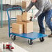 A man pushing a blue Lavex platform truck with boxes.