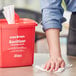 A person using a Noble Products disposable center pull dry wipe to clean a table.