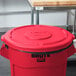 A red Rubbermaid Brute lid on a red trash can.