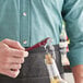 A person using an Acopa waiter's corkscrew to open a bottle of wine with a cork on a counter in a cocktail bar.