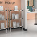 A woman standing in front of a Metro heated takeout station with shelves full of bags.