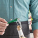 A person uses an Acopa Waiter's Corkscrew with a green metal handle to open a bottle of wine on a counter.