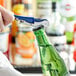 A person using a blue and silver Acopa Waiter's Corkscrew to open a green bottle of beer.