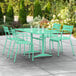 A Lancaster Table & Seating seafoam green table with 4 arm chairs on a patio.