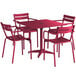 A red Lancaster Table & Seating outdoor table with a black umbrella hole on an outdoor patio with four red chairs.