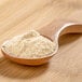A wooden spoon filled with red apple powder.