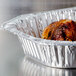 A Durable Packaging oval foil roast pan with a cooked chicken inside.