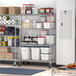 Regency chrome mobile wire shelving unit in a school kitchen with food items on shelves.