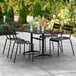 A black Lancaster Table & Seating outdoor table with chairs on a patio.