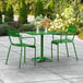 A Lancaster Table & Seating green table and chairs on a patio.