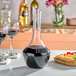 A Franmara Fleurie crystal decanter filled with red wine on a table with a plate of fruit and crackers.