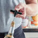 A person using a black plastic pocket corkscrew to open a bottle of wine.