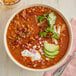 A bowl of Whitey's Beef Chili with beans topped with sour cream and avocado.