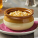 An Acopa stoneware bowl filled with food on a table.