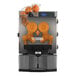 A Zumex Essential Pro juicer with an orange in the automatic feed.