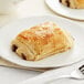 A close-up of a White Toque chocolate croissant on a white plate.