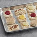 A tray of White Toque mini pastries with 5 flavors on a gray surface.