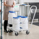 A woman using an aluminum dolly to transport white Choice ice totes.