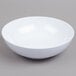 A white Carlisle melamine bowl on a gray surface.