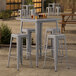 A Lancaster Table & Seating outdoor table and barstools on a patio.