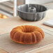 A Baker's Mark fluted bundt cake in a cake pan on a wire rack.