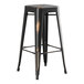 A Lancaster Table & Seating distressed copper bar height table with two black metal backless barstools with wooden seats.