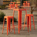 An outdoor table with barstools. The table and barstools are orange.