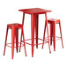 A red square Lancaster Table & Seating bar table with 2 red metal backless barstools.